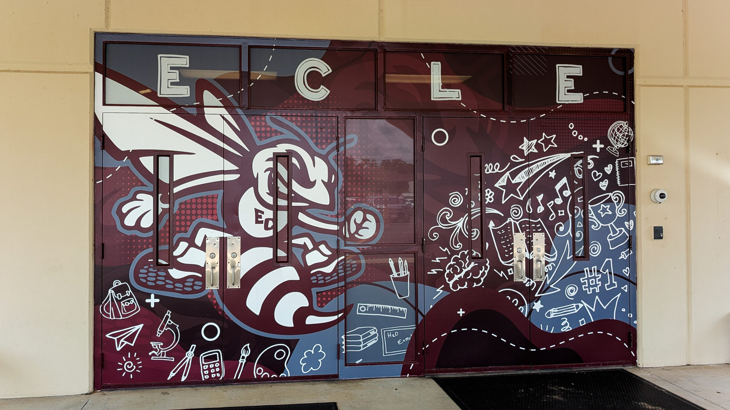Custom front entrance door wrap at East Central Lower Elementary in Moss Point, MS, featuring a hornet mascot and school-themed graphics in maroon, gray, and white.