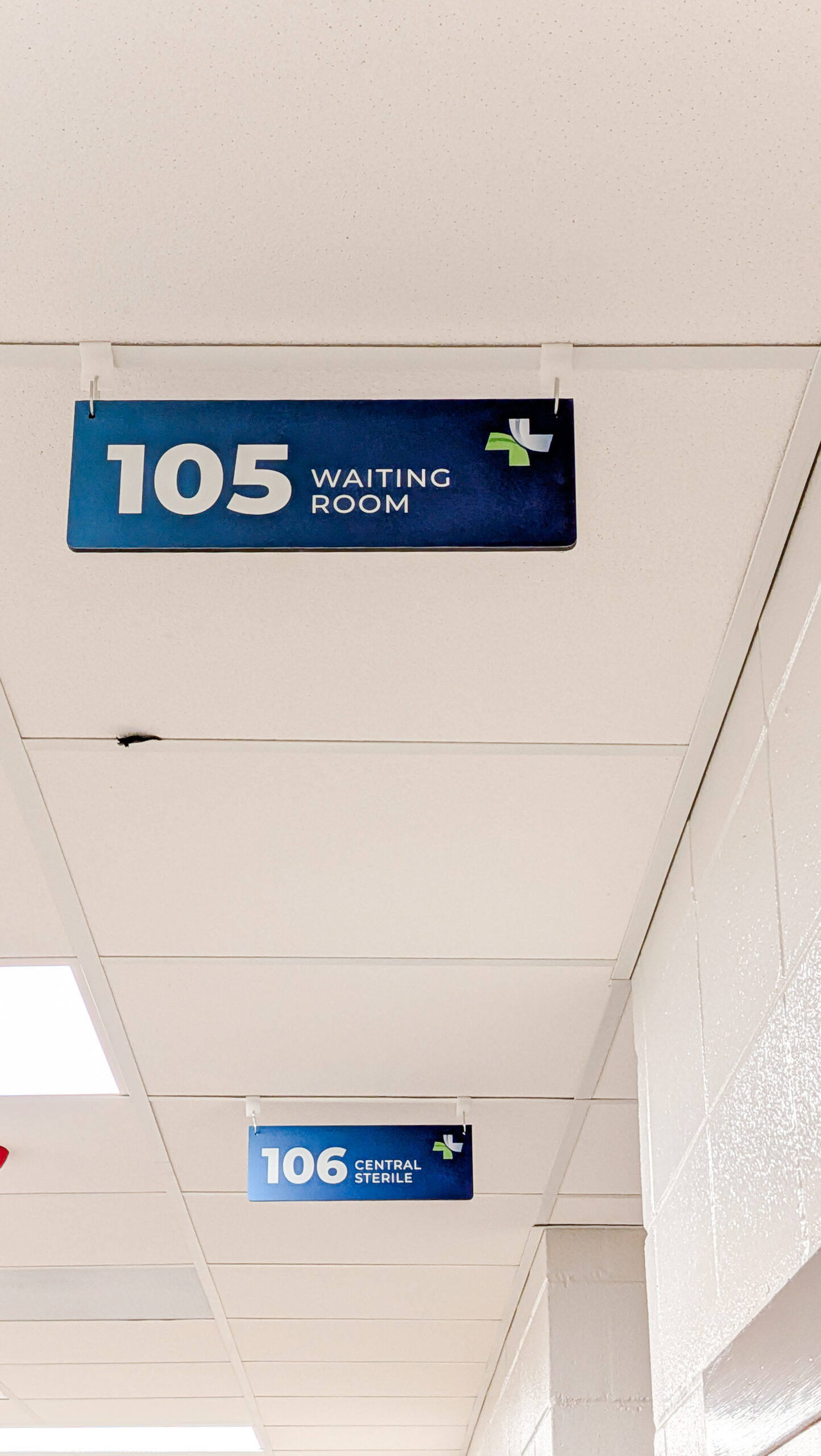 Hanging classroom signage in a hallway identifying rooms at a technical education facility.